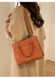 Dettaglio della borsa tote in pelle caramello con tracolla e fianchi a soffietto eleganti