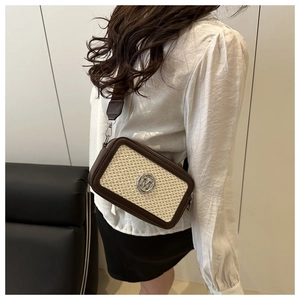 Detailed close-up of brown leather and beige woven fabric on a crossbody bag with M logo