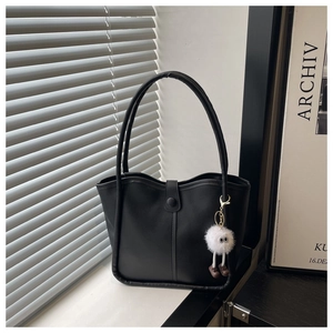 Detail of black minimalist tote bag with smooth matte finish and cute plush charm pendant