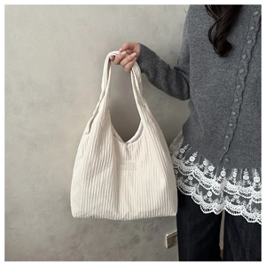 Close-up of beige pleated tote bag featuring a Fashion label on soft fabric texture
