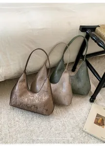 Detailed view of large metallic Hobo bags in bronze, beige and green with vertical textures