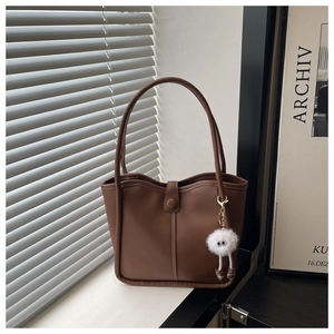 Close-up of brown PU leather tote bag with magnetic closure and plush doll pendant