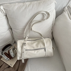 Minimalist off-white cylinder shoulder bag with silver zippers and adjustable strap