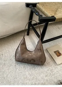 Detail of a brown hobo bag with vintage textured metallic finish on a plush carpet