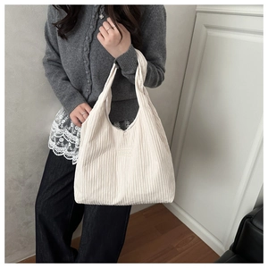 Detail of off-white pleated tote bag showing fabric texture and FASHION logo tag