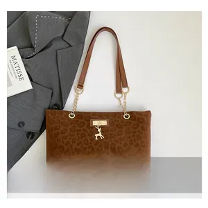 Detail of leopard print tote bag with golden deer pendant and metal chain strap