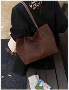 Detail of dark brown faux suede tote bag with slim shoulder straps in an autumn setting