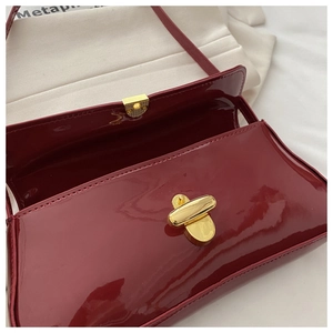 Detailed view of burgundy patent leather bag with a glossy finish and gold twist lock