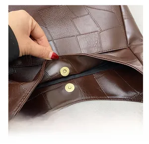 Close-up of golden magnetic snap closure on a brown patchwork leather tote bag