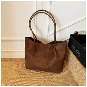 Detailed close-up of dark brown suede shoulder bag with minimalist design and slim straps