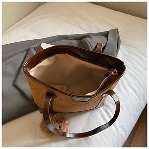 Top view of large brown tote bag with logo pattern, showing spacious interior and plush bear