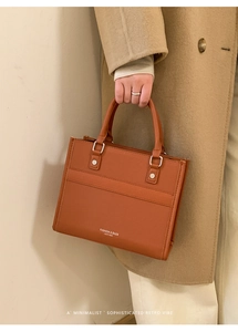 Brown leather tote bag featuring elegant stitching and white fashion typography detail