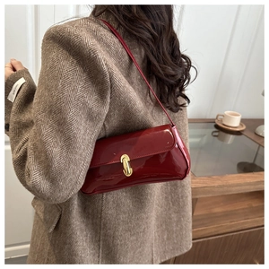 Detail of dark red patent leather shoulder bag with golden J-shaped metal buckle