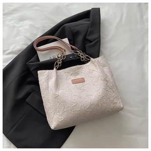 Detail of star-patterned texture and pink logo on large beige tote bag with chain