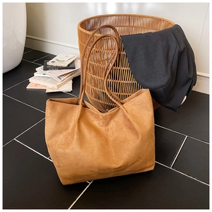 Close-up of brown suede tote bag with central vertical seam detail in home setting