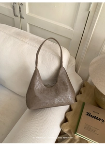 Detailed close-up of brown hobo bag with vertical ribbed texture on a white sofa
