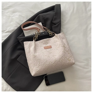 Detail of floral texture tote bag with pink leather handle and gold chain strap