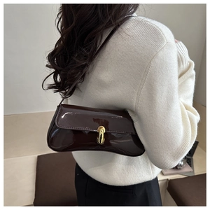 Detail of a dark brown patent leather baguette bag with a gold buckle and shoulder strap