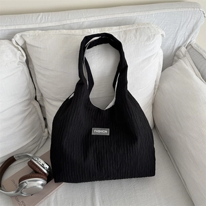 Sac fourre-tout noir plissé léger avec étiquette FASHION sur un canapé en tissu blanc
