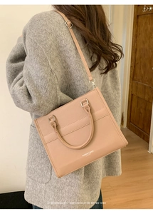Dettaglio della borsa a tracolla in pelle rosa con doppi manici e cinturino sul modello