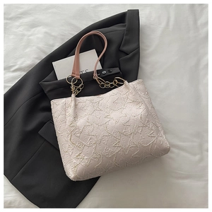 Detailed macro of star-pattern embroidery on off-white tote bag with pink leather strap