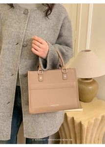 Dettaglio della borsa tote in pelle beige con borchie in metallo e scritte sulla borsa
