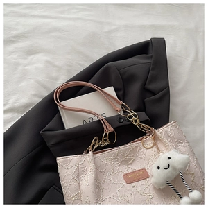 Close-up of pink textured tote bag with metal chain strap and cute cloud plush charm