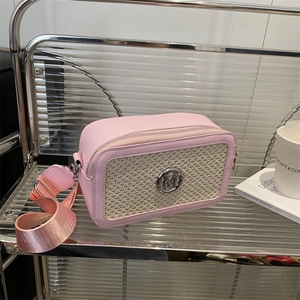 Pink leather and beige woven crossbody camera bag with silver M logo on a modern shelf