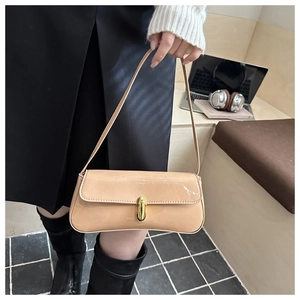 Close-up of beige patent leather shoulder bag with gold cylindrical metal buckle