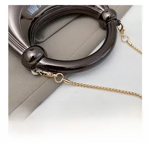 Detail of high-gloss dark grey round handle with gold lobster clasp and chain link