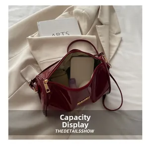 Détail montrant la capacité intérieure du sac cylindrique en cuir verni bordeaux