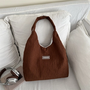 Sac fourre-tout marron à rayures minimaliste avec texture plissée posé sur un canapé