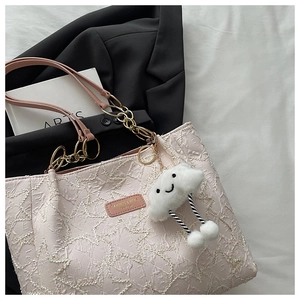 Detail of pink tote bag featuring ripple texture fabric and gold chain handle