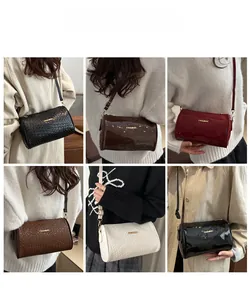 Detail of cylinder crossbody bags in patent leather, woven and embossed textures