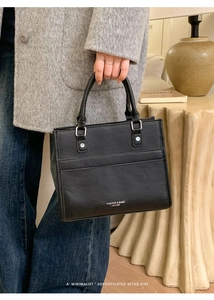 Dettaglio della borsa tote nera in pelle martellata con manici spessi e fibbie argentate
