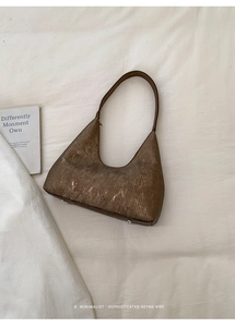 Macro detail of brown retro underarm bag showing textured pattern and bottom metal studs