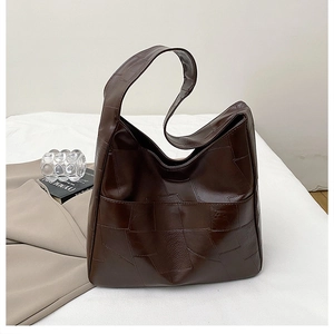 Detail of dark brown leather tote bag showing high-quality pebbled texture and stitching