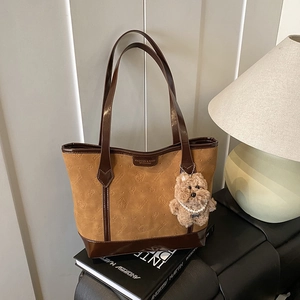 Brown suede tote bag with bear charm and embossed pattern on minimalist background