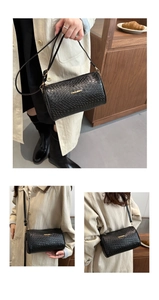 Detail view of black woven texture cylinder bag with gold fashion lettering logo