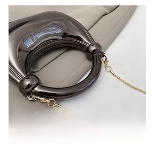 Close-up of sleek grey metallic evening bag with round handle and gold chain strap