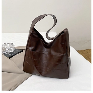 Detail of dark brown tote bag with geometric leather patchwork on white bedding