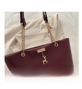 Détail d'un sac cabas bordeaux avec pendentif cerf doré et bandoulière en chaîne