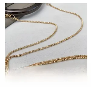 Macro shot of high-quality polished gold metal chain strap detail on luxury clutch bag
