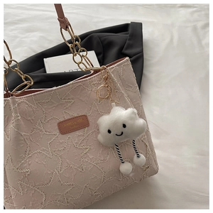 Close-up of pink star-patterned tote bag with gold chain and white cloud charm