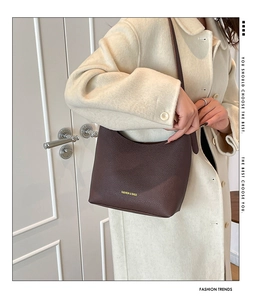 Close-up of deep brown lychee texture leather shoulder bag with gold lettering detail