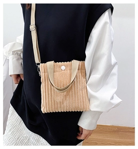 Detailed texture of beige corduroy mini tote bag with silver buckle and round snap button
