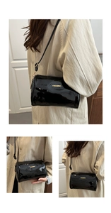 Close-up of glossy black leather cylinder bag with gold Fashion logo and metallic strap