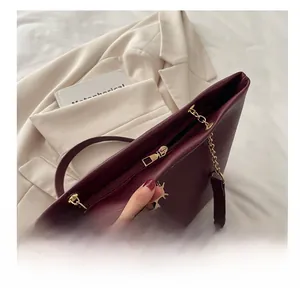 Détail de la fermeture éclair dorée lisse sur un sac cabas en cuir bordeaux