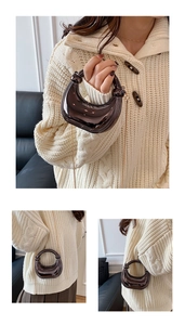 Detail view of mirror finish crescent handbag with hollow round handle and chain strap