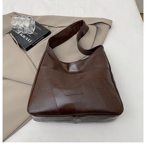 Detail of dark brown patchwork tote bag showing sleek synthetic leather and wide strap